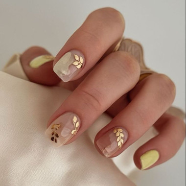 Delicate milky manicure with golden leaves